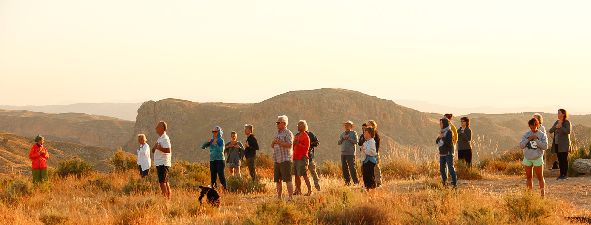 group practicing Qi Gong on a hillside in Granada at sunrise